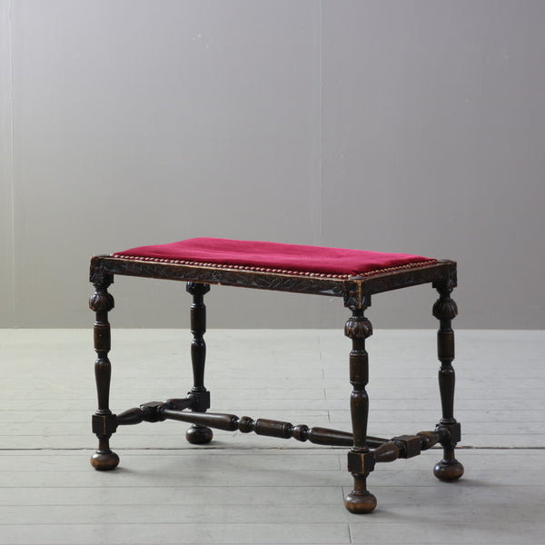 ワインレッドのスエード生地の座面の木製アンティークスツールの斜めからの全体画像