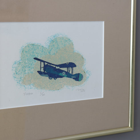斜めアップで見る飛行機モチーフ版画額装。フレームと作品の質感が伝わる画像。